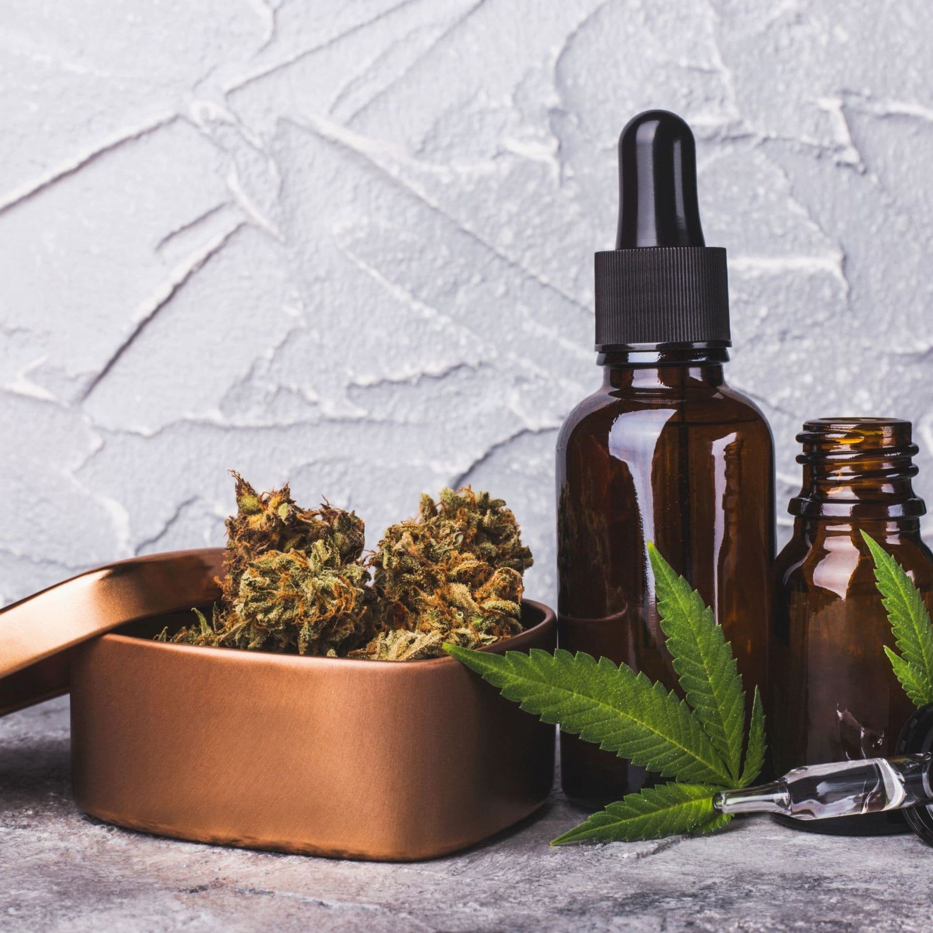 coffret cadeau contenant des fleurs de CBD posé près de flacons d'huile de cbd et d'une feuille de cannabis